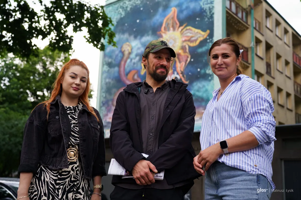 Na zdjęciu od lewej: Sandra Gwizdała, Mikołaj Rejs, Anna Gawlas. W tle mural "Zegar Słonecznikowy" przy ul. Siemaszki 37 w Krakowie