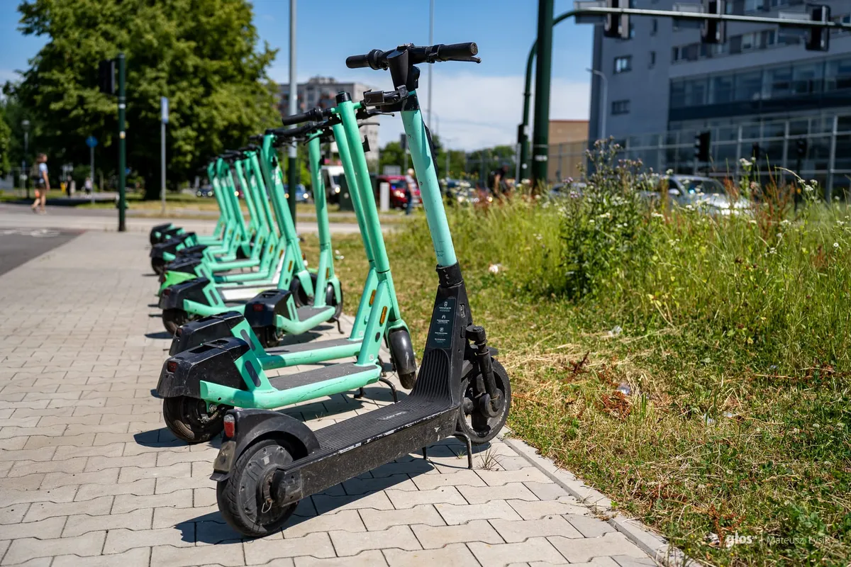 na zdjęciu rząd hulajnóg elektrycznych na chodniku